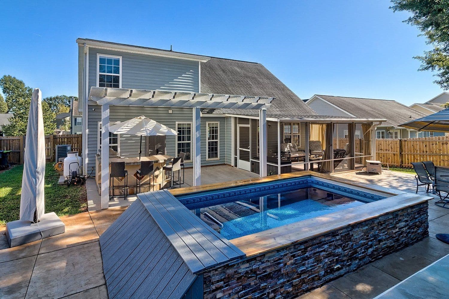 Backyard swim spa with a wooden deck and pergola