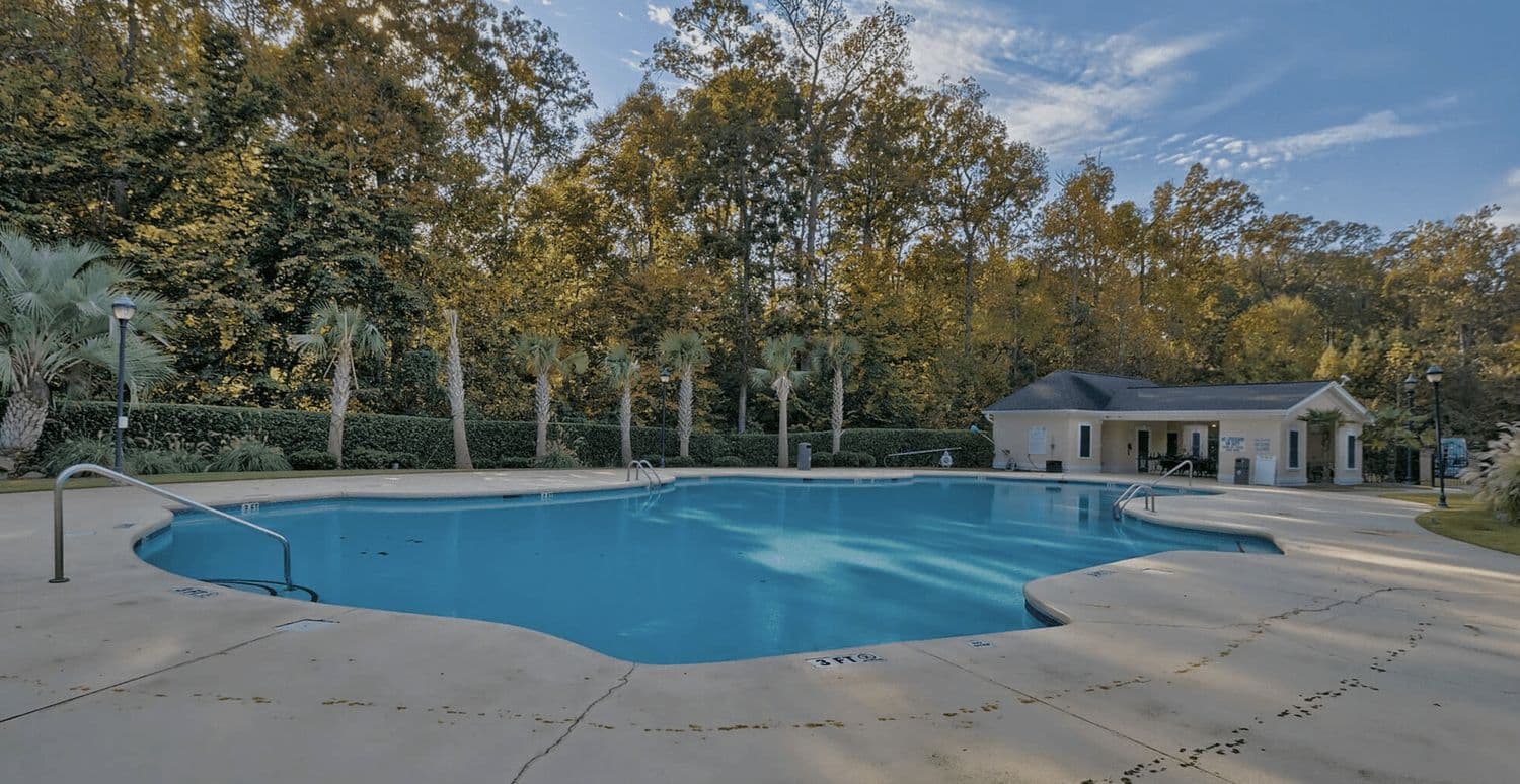 Large outdoor swimming pool with a pool house and autumn-colored trees