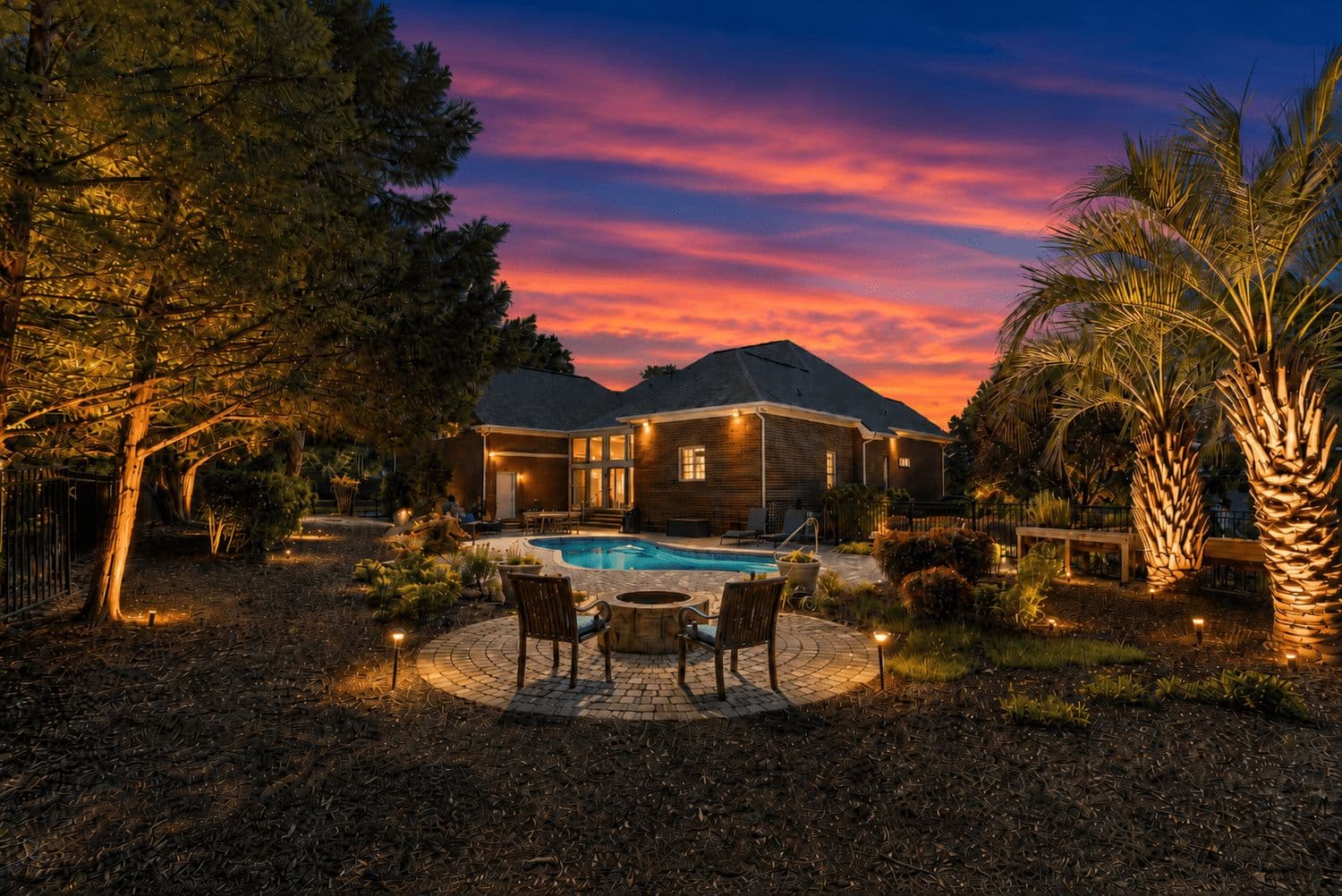 Lit patio at night with a dining set and pool