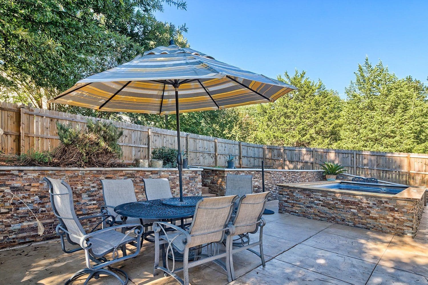 Patio with stone retaining wall, dining table and striped umbrella
