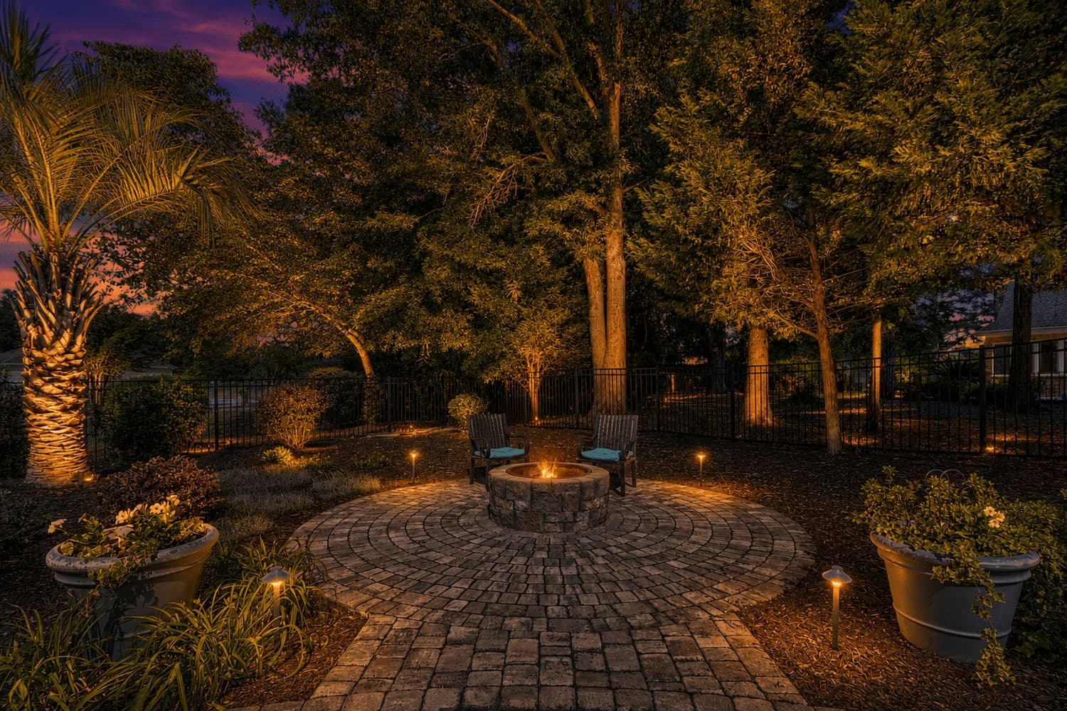 Stone patio with a fire pit among trees at night