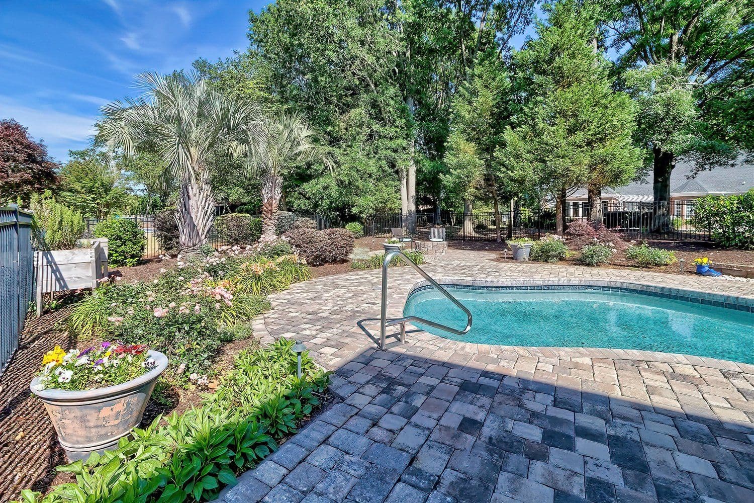 Swimming pool area with brick pavers and palm trees