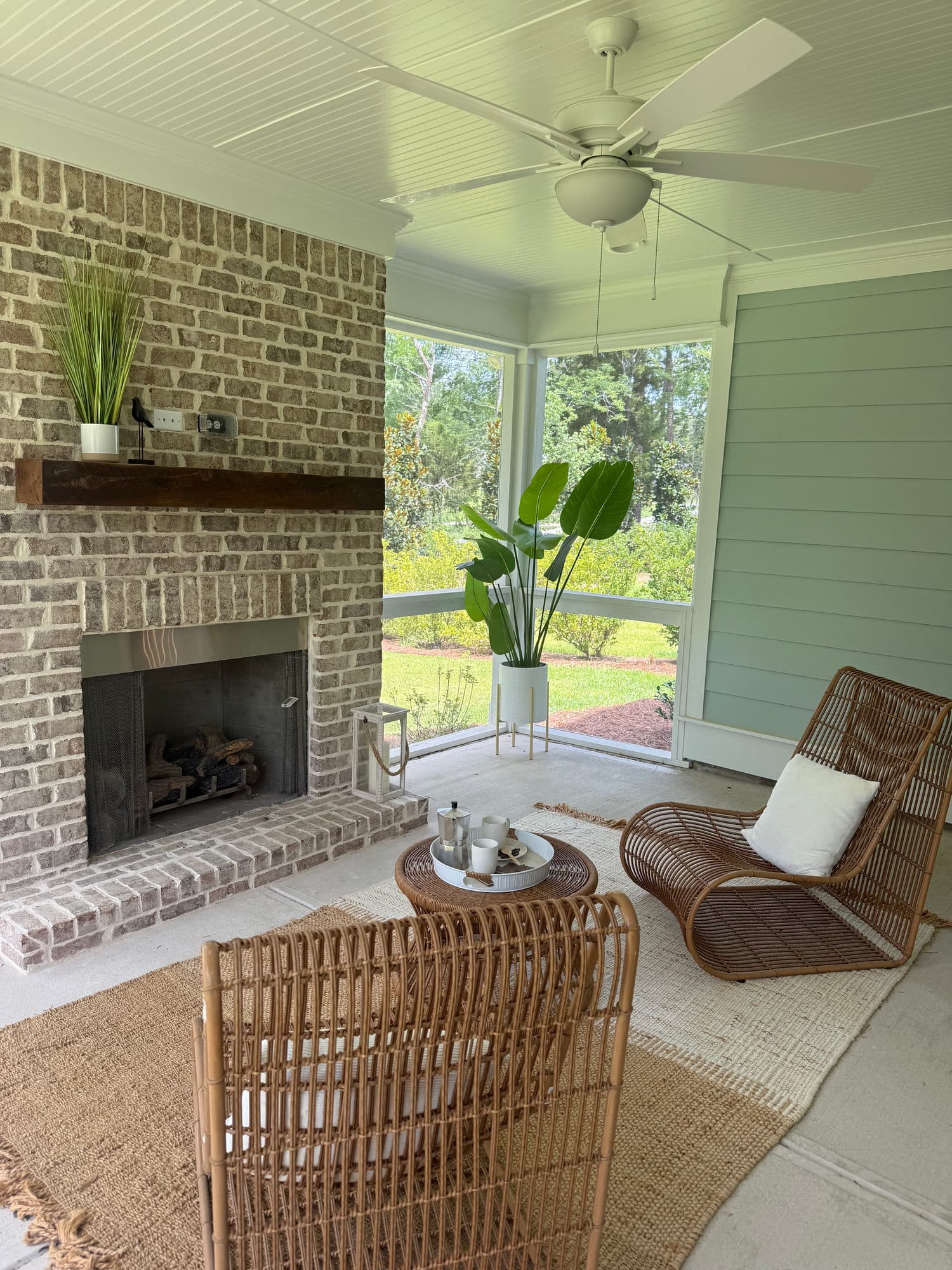 A screened porch with a brick fireplace and wicker chairs
