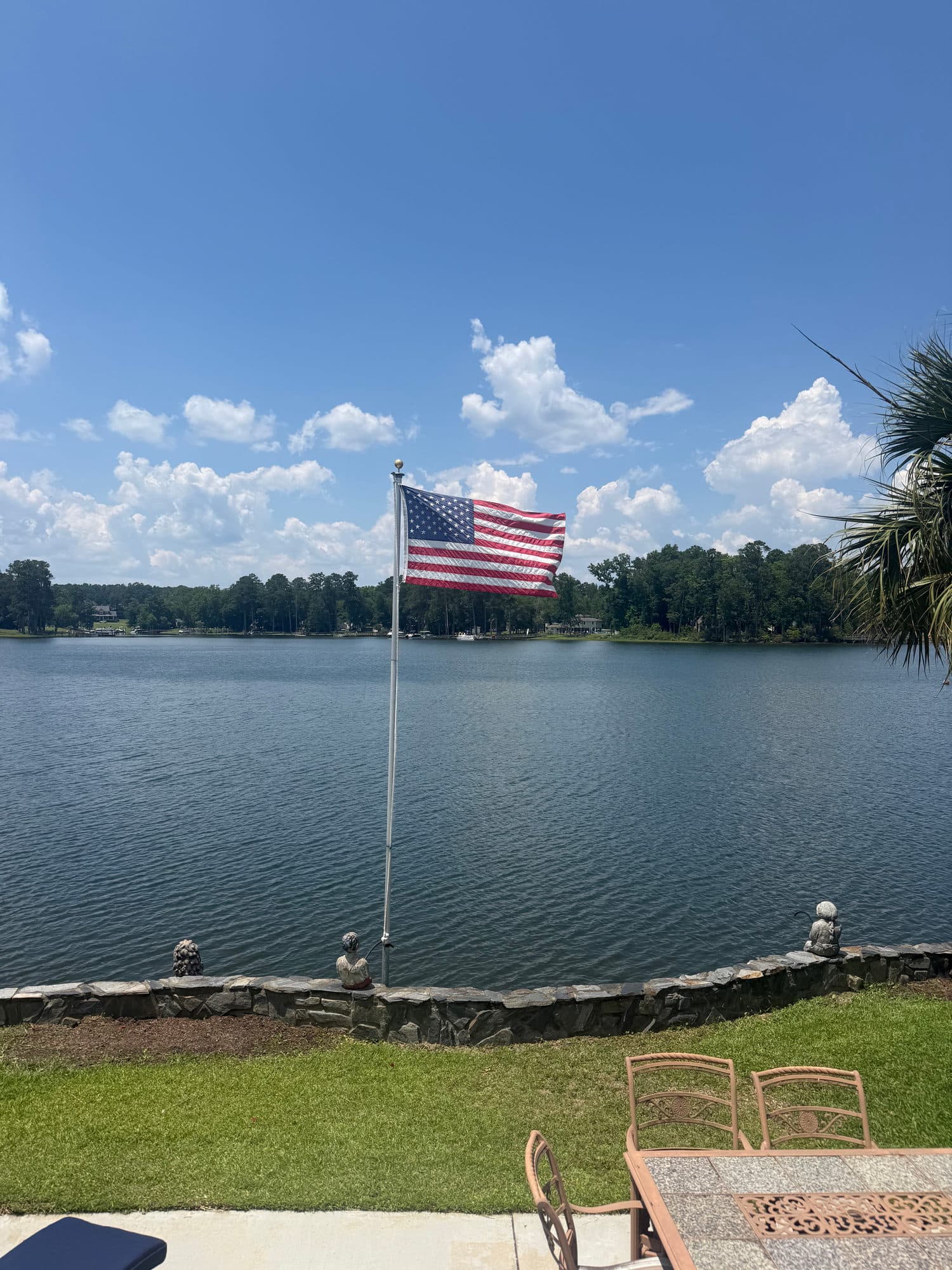 A lawn at the water with a flag against the far shore