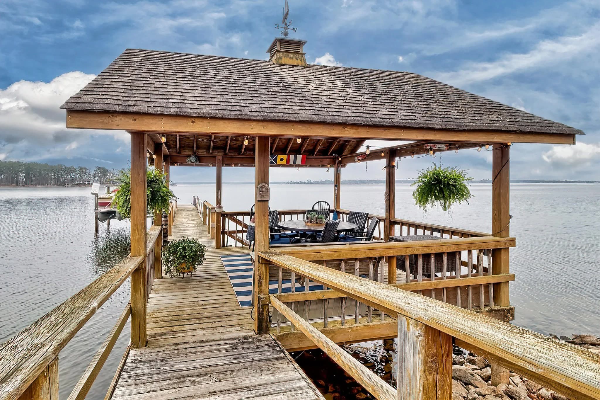 A covered dock with a dining table on the water