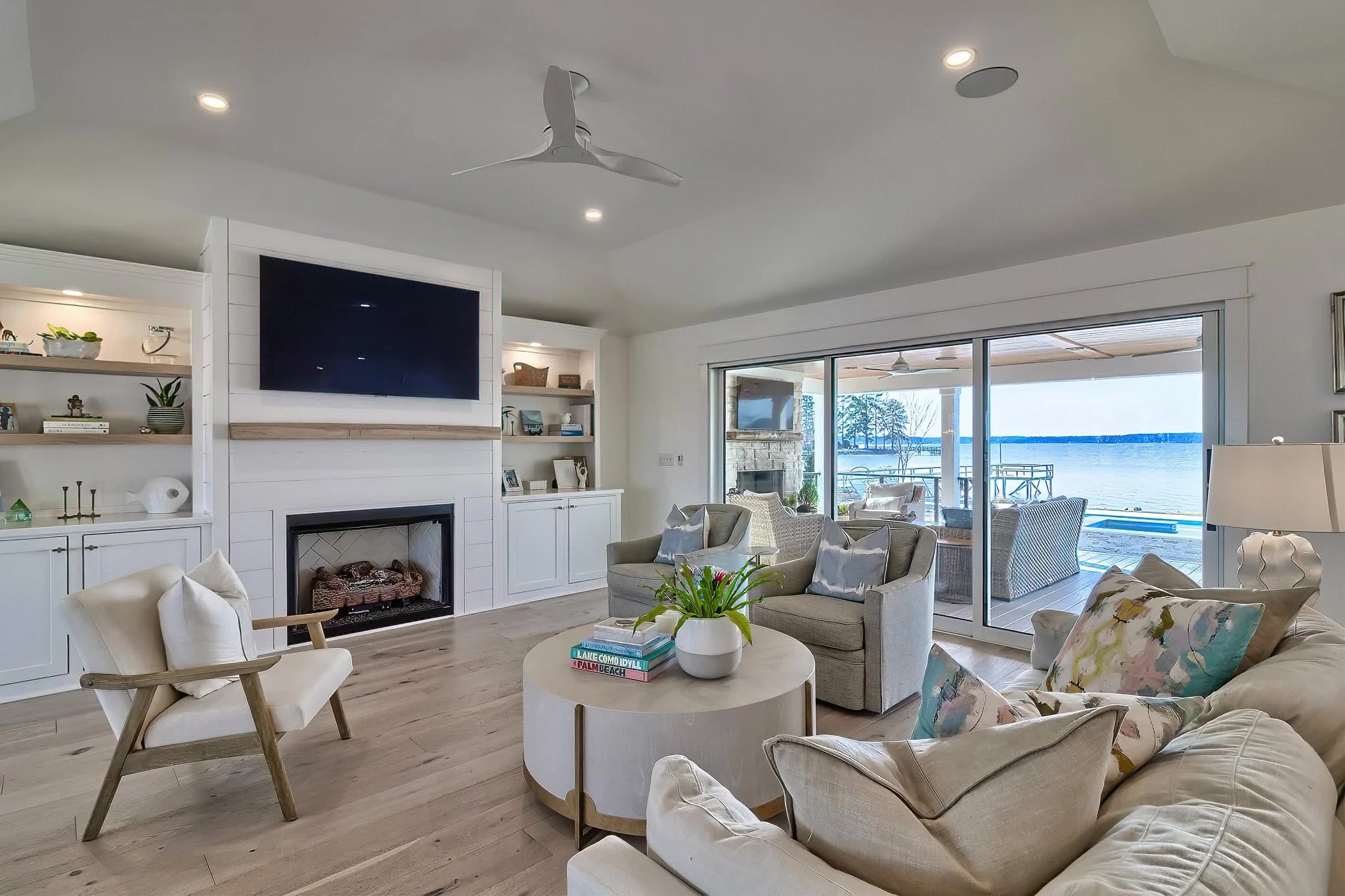 A living room looking out to a deck, pool, and the lake