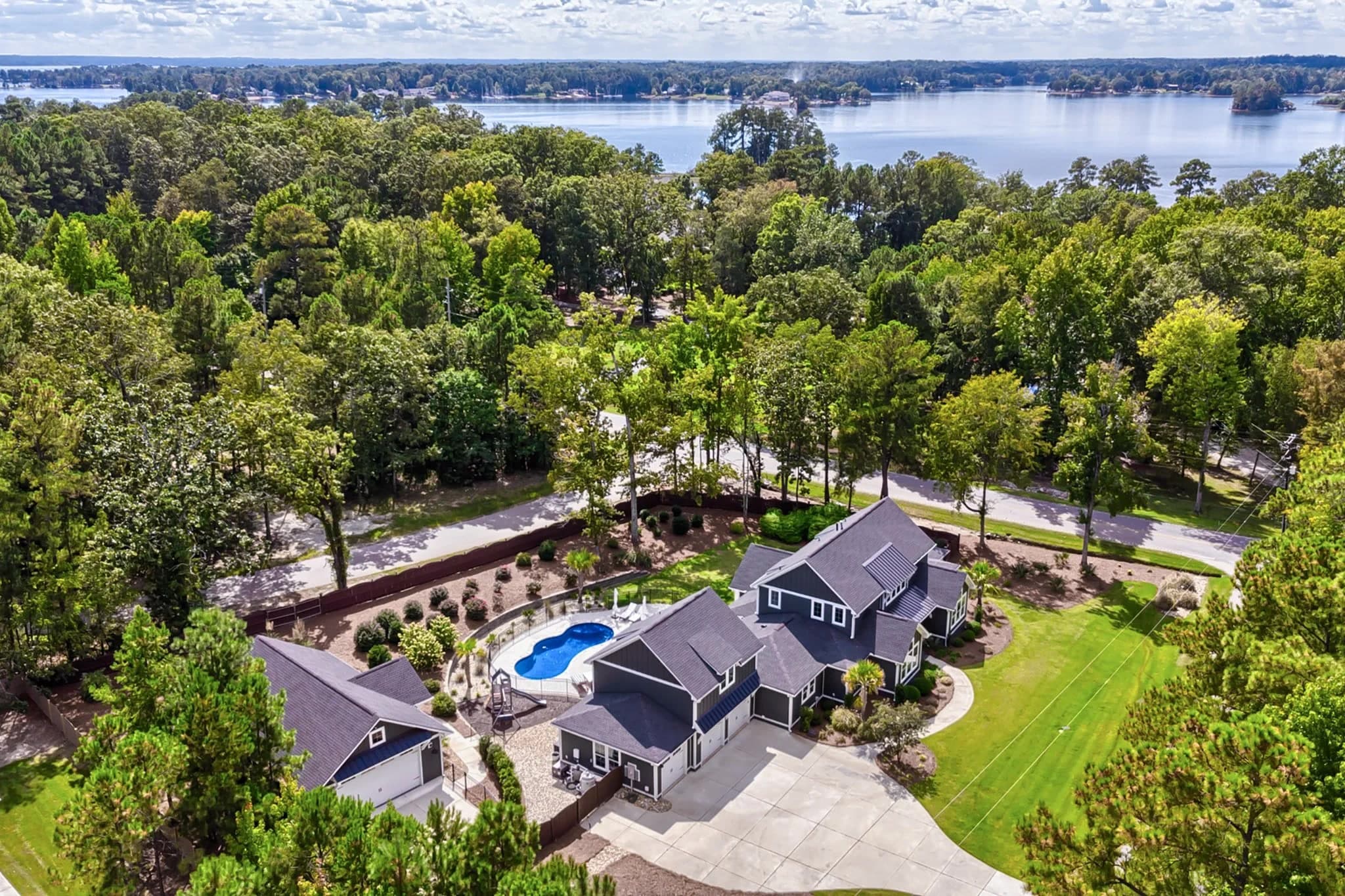 A house with a pool set back from the lake by a road