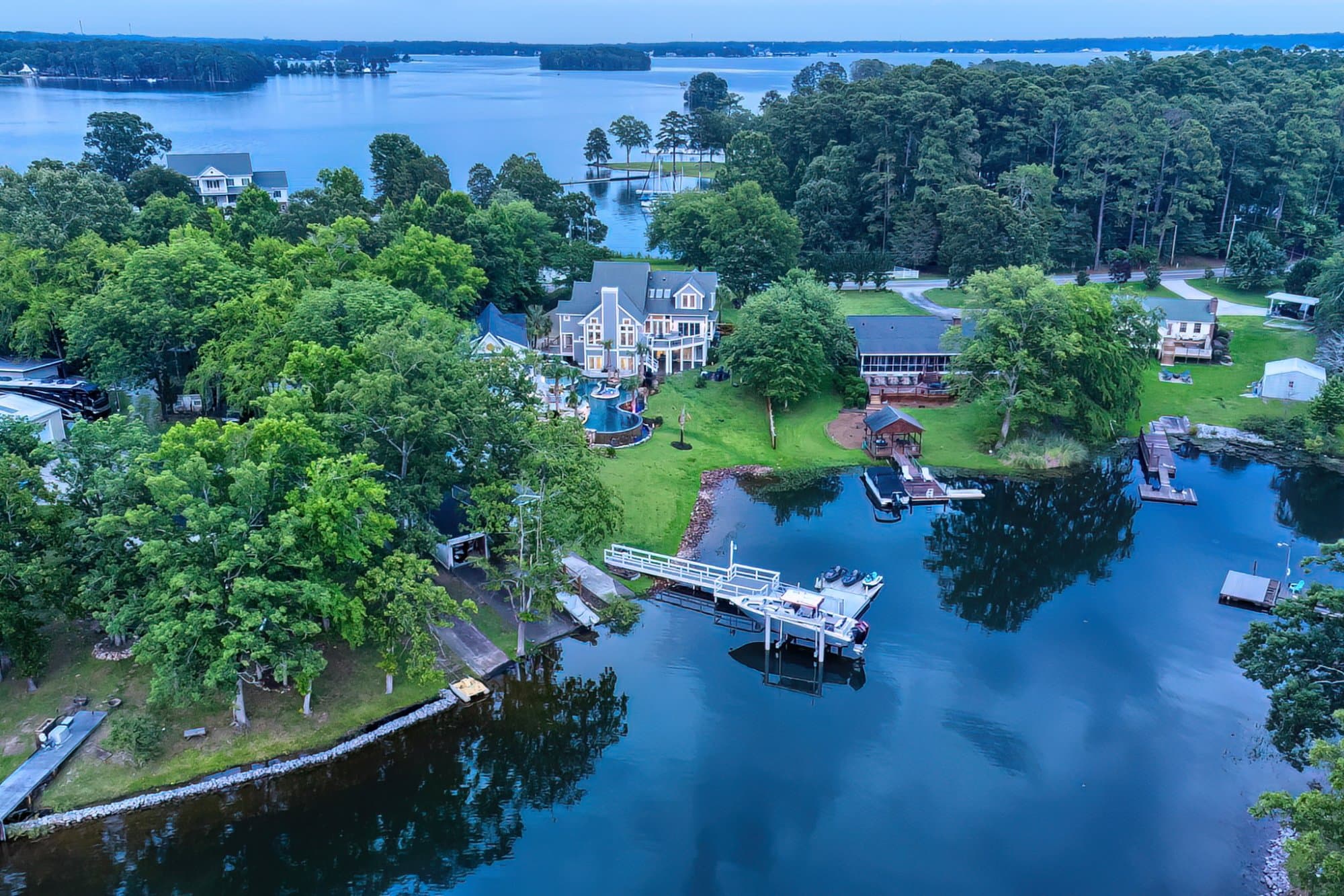 Dusk aerial of a luxury estate with a swimming pool, private dock, boat lift, and jet skis, Lake Murray, SC