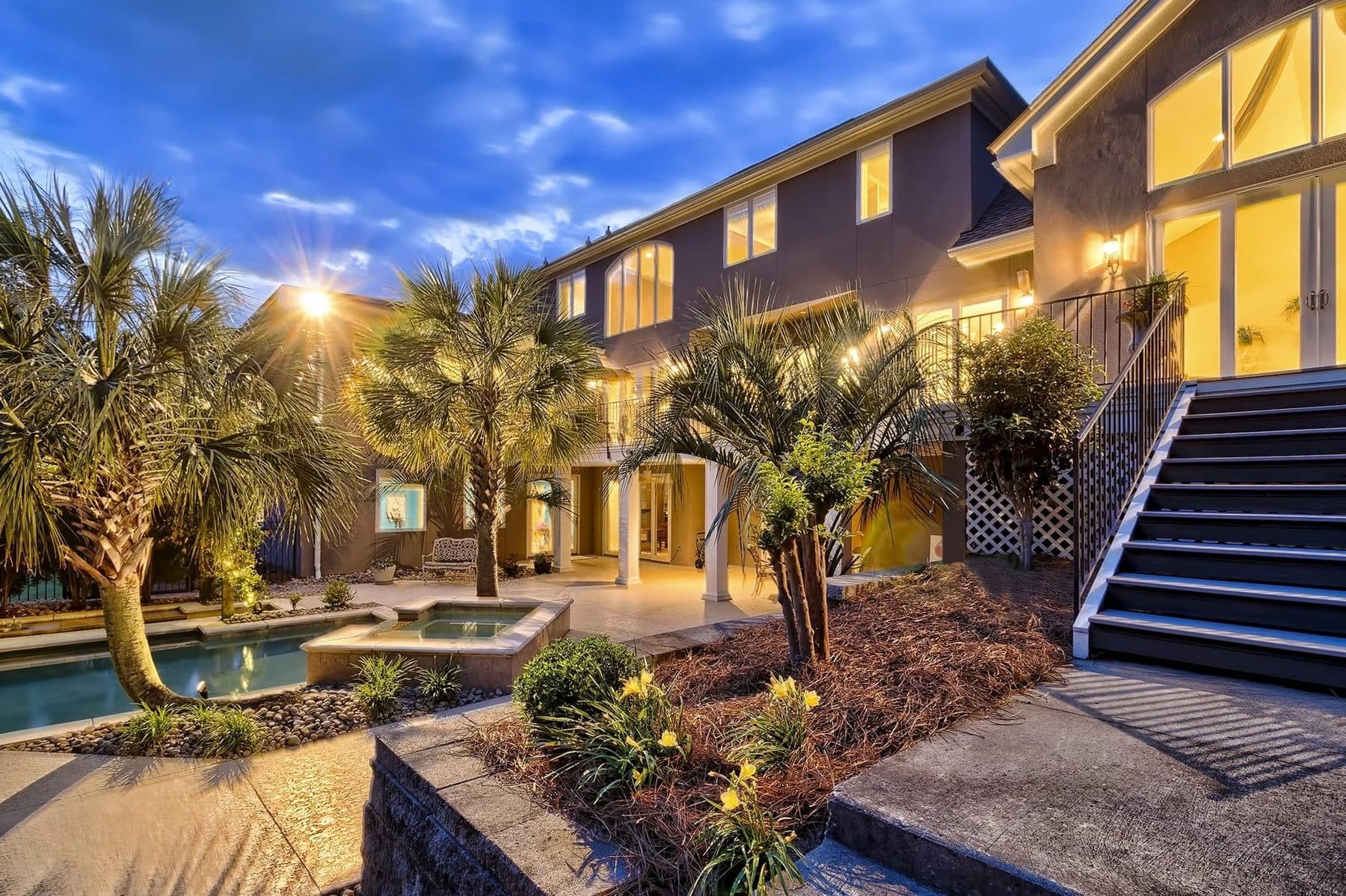 A backyard pool behind a house at dusk