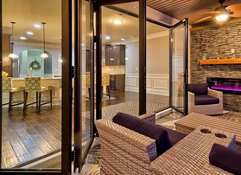 A covered patio with a stone fireplace opening to the kitchen