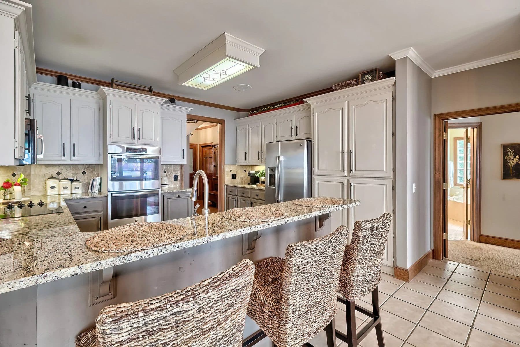 A two-tone kitchen with a granite breakfast bar
